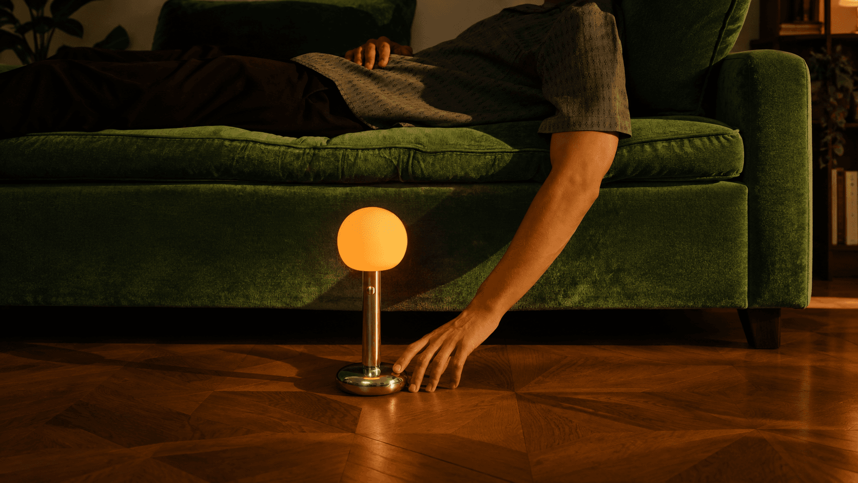 Warm sculptural lamp beside a green sofa